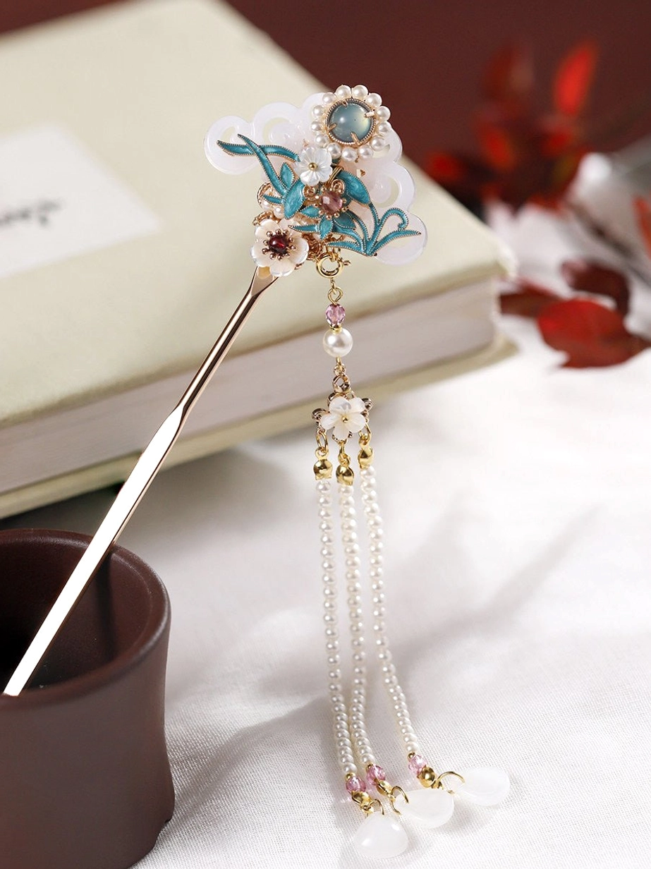 Cloisonne orchid tassel Chinese hair stick for Hanfu displayed on a book with blue floral enamel-style ornament, white accents, pearl-style tassel and gold-tone pin