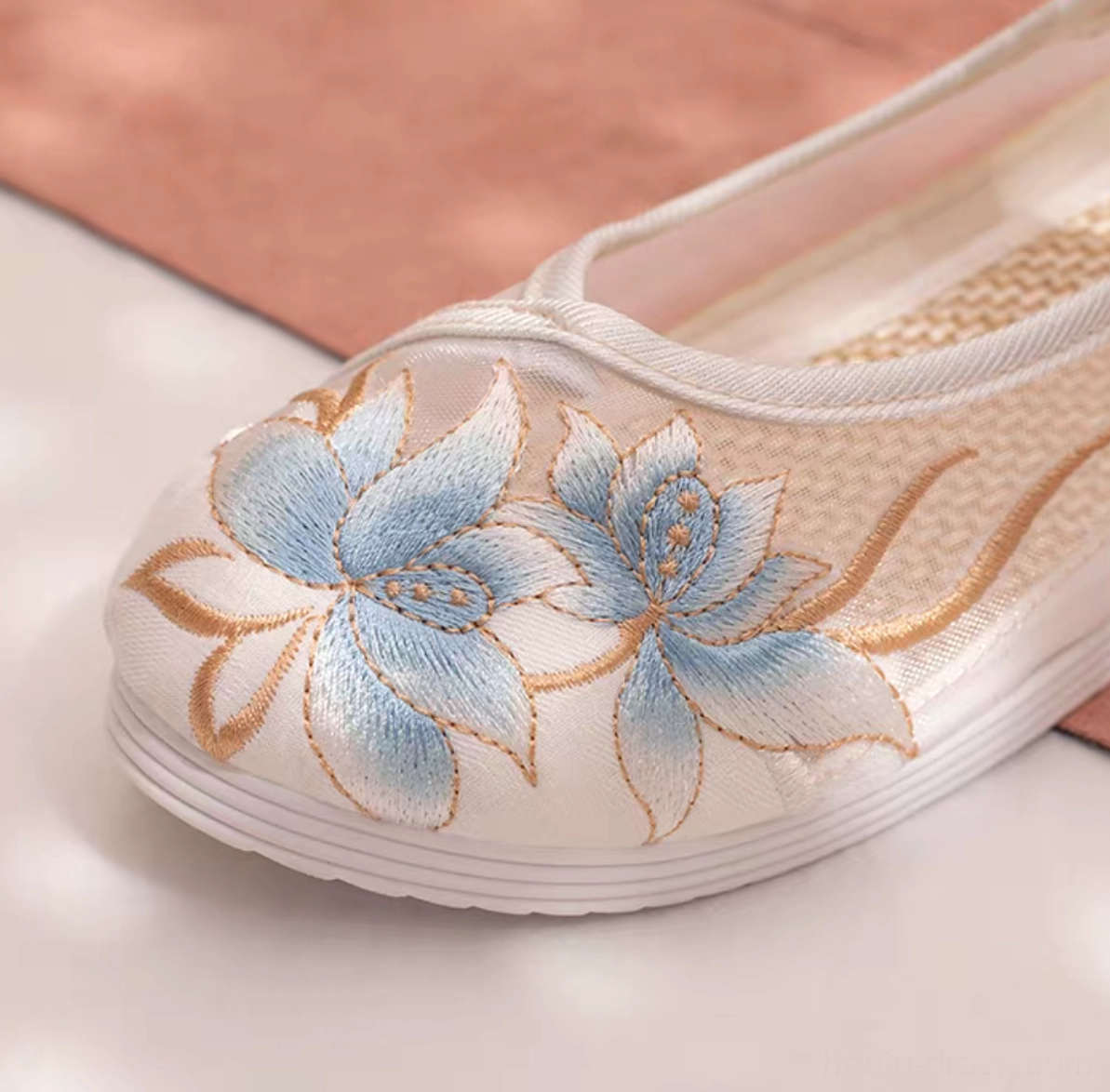 Close-up of embroidered Chinese Hanfu shoe showing detailed blue lotus with golden outlines, breathable mesh fabric, rounded toe, and woven inner insole