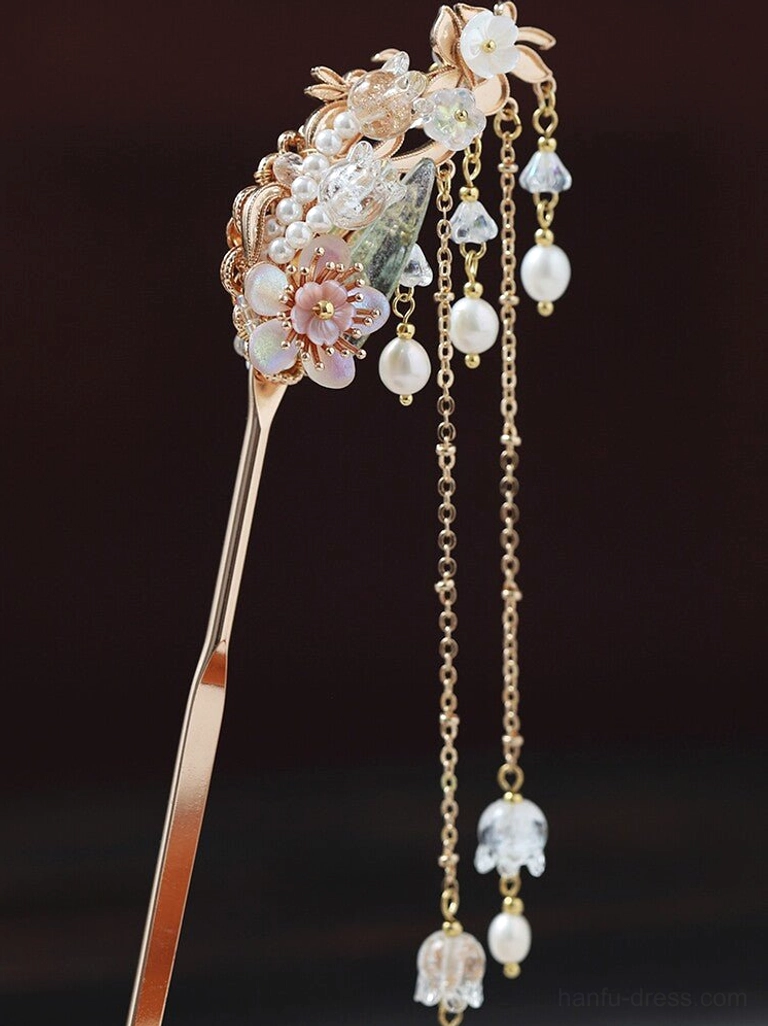 Close-up of champagne gold Chinese hairpin shaft with glazed leaves, pink floral carvings, pearl details, crystal ornaments, and tassels