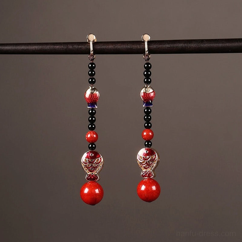 Close-up of Chinese koi fish earrings featuring red enamel fish black beads gold-toned details and round red bottom pendants