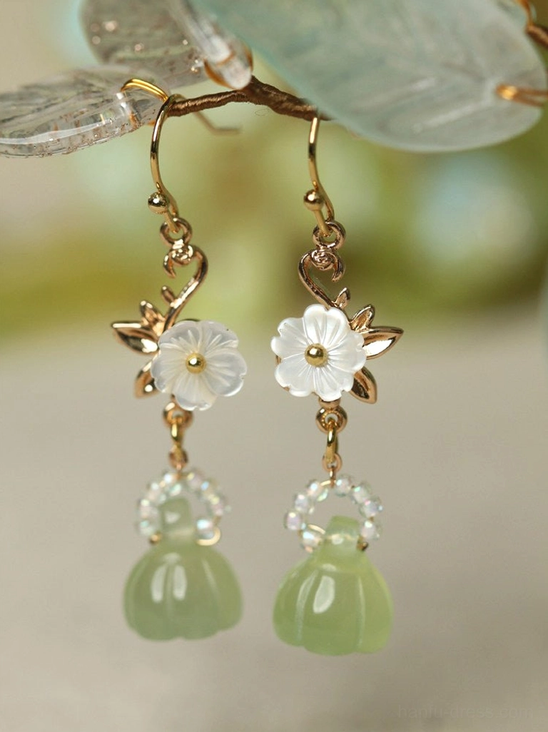 Close-up lotus pod Chinese earrings with gold ear hooks carved white shell flowers clear bead clusters and matching green drops