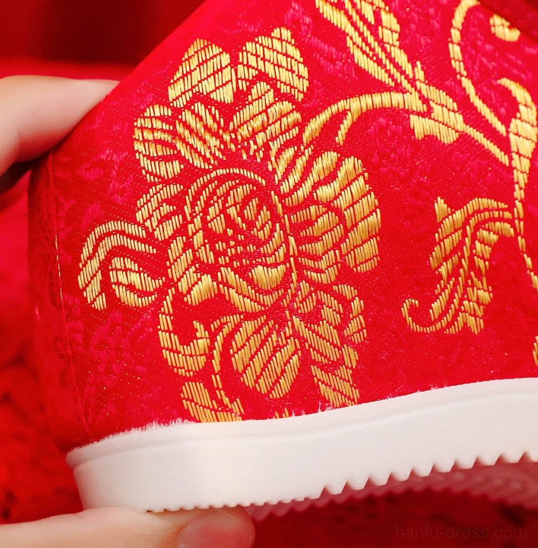 Close-up of scarlet Chinese bridal Hanfu shoe showing detailed golden peony embroidery, soft fleece lining, canvas upper, and textured anti-slip rubber outsole