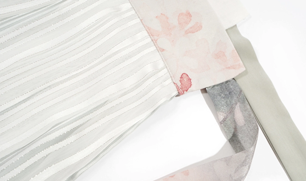 Close-up of the Cloud Pavilion hanfu lower garment showing a pleated light gray striped skirt, pink floral waist panel, and gray-green fabric waist sash
