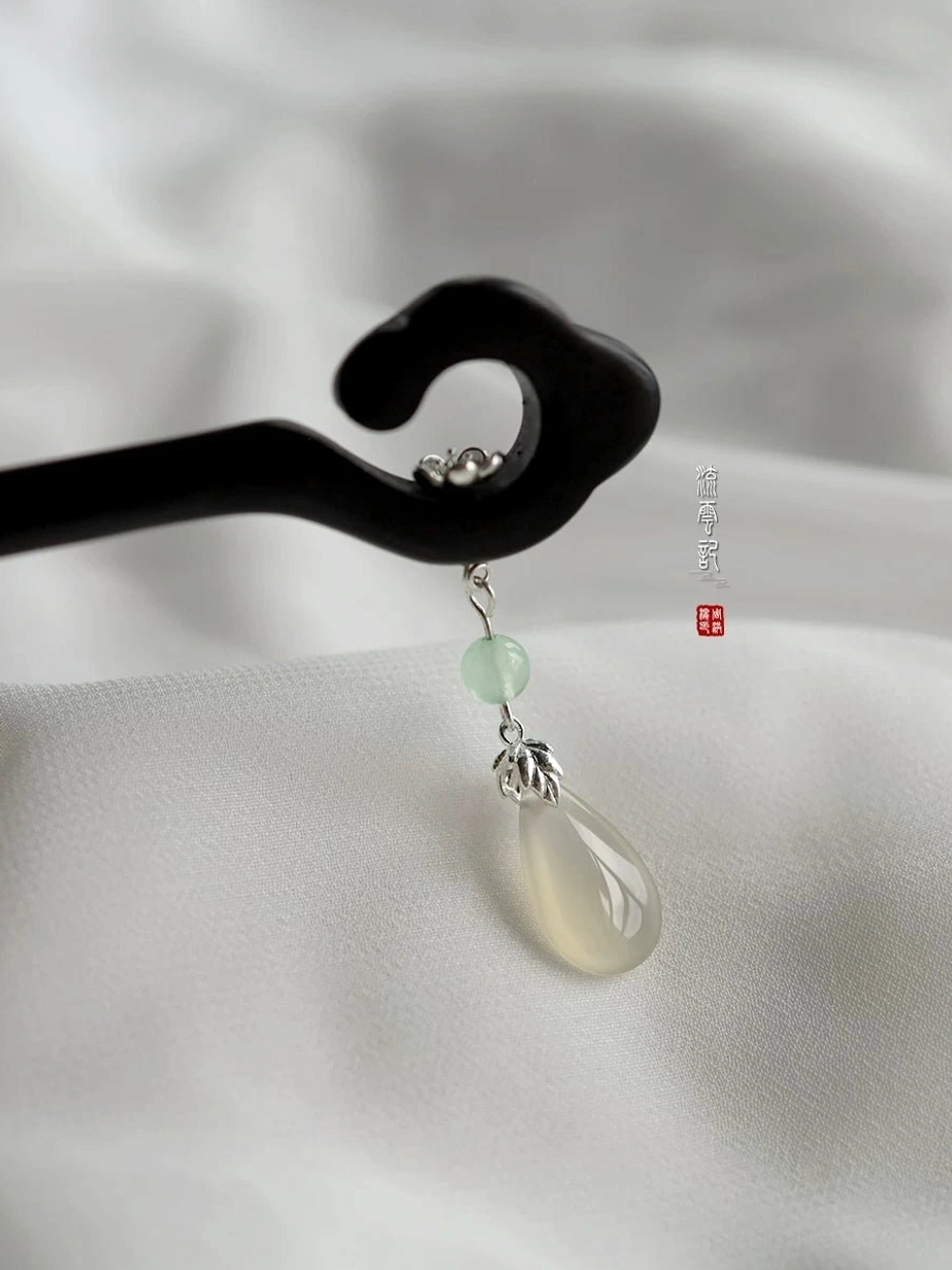 Close-up detail of cloud-top Chinese wooden hair stick pendant with silver-tone flower, light green bead, and translucent drop charm