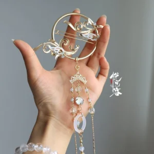 Hand holding Cold Moon Chinese style Hanfu back hair pin with gold-tone cloud motif, white decorative details, translucent bead chains, and jade-style circular pendant
