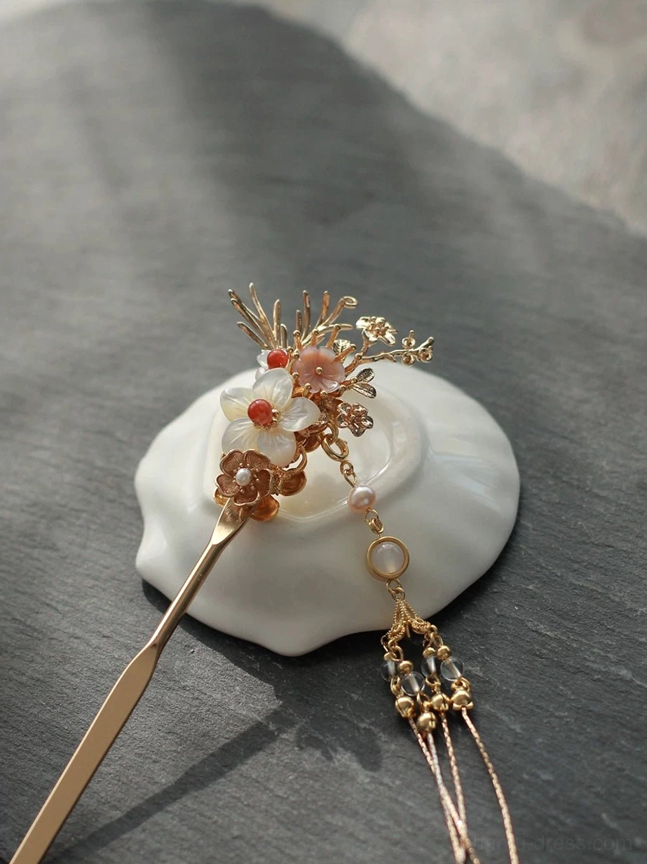 Compact Hanfu hair stick featuring a small gold floral ornament, short pearl tassel, and delicate bead accents photographed on a dark slate background