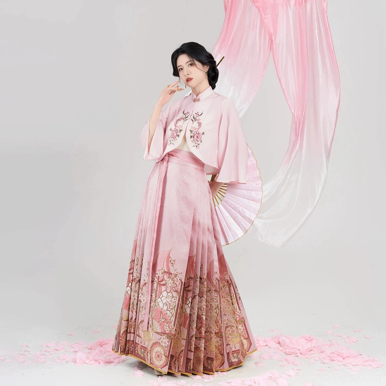 Three-quarter front view of a complete Chinese hanfu blouse and mamian skirt outfit with floral embroidery and traditional folding fan