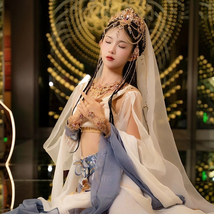 Complete Dunhuang Hanfu jewelry set worn with a flying fairy outfit, showing the coordinated crown, neck jewelry, bracelet, gold-tone details, and layered tassels in a warm oriental setting