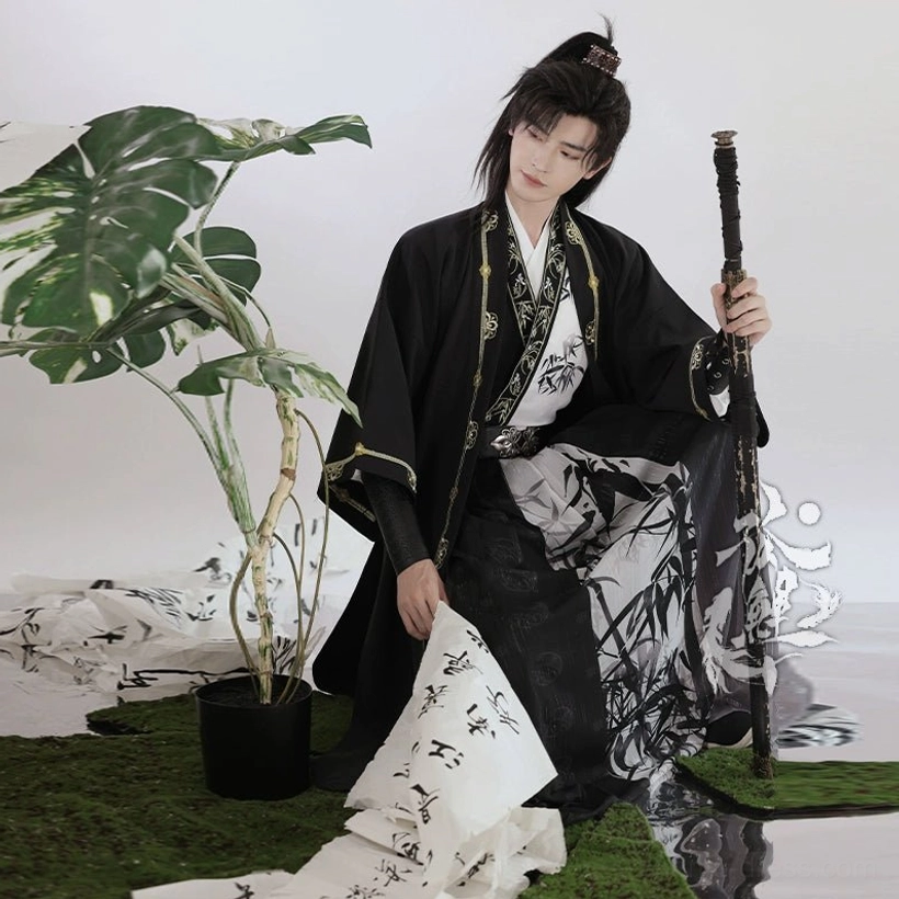 Three-quarter view of a male model wearing a complete black wuxia Hanfu outfit with bamboo patterned lower garment and sword
