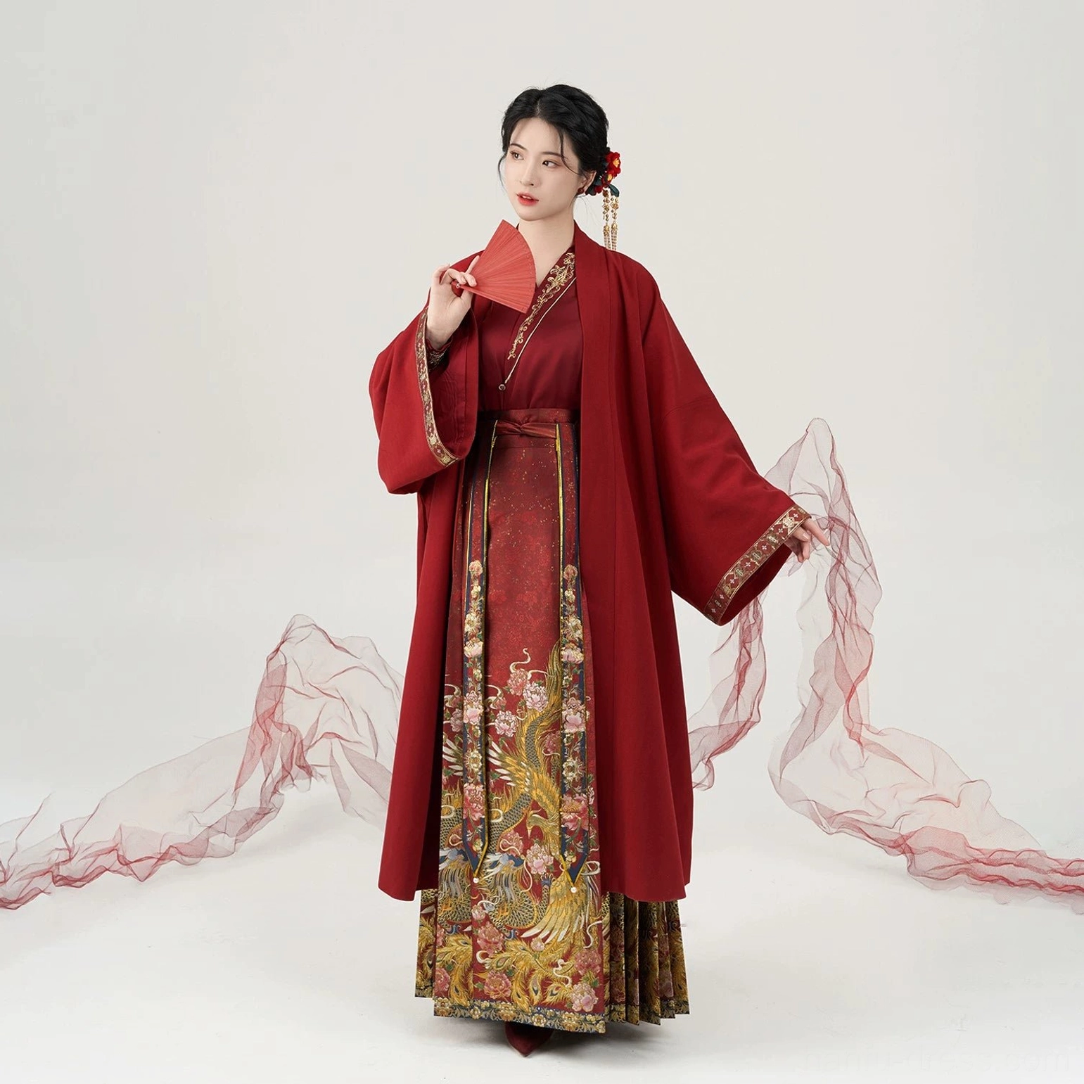 Complete Ming Dynasty wedding Hanfu set shown in full front view with red folding fan, flowing Mamian skirt, and red studio drapery