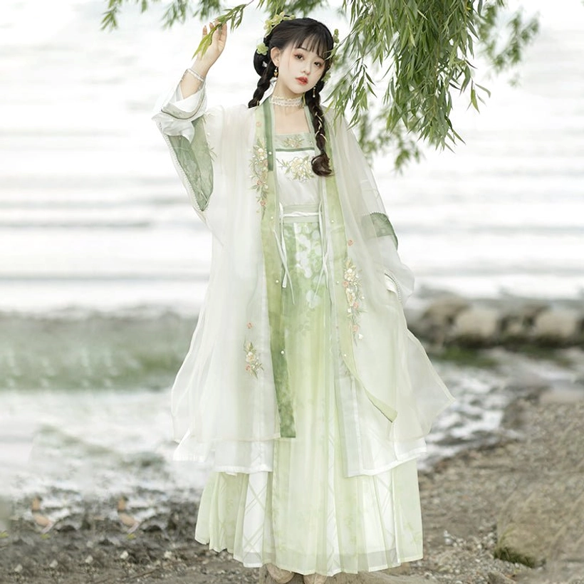 Rear view of complete Song Dynasty Qiyao Ruqun Hanfu set with layered skirt hem and coordinated green white tones beside willow branches