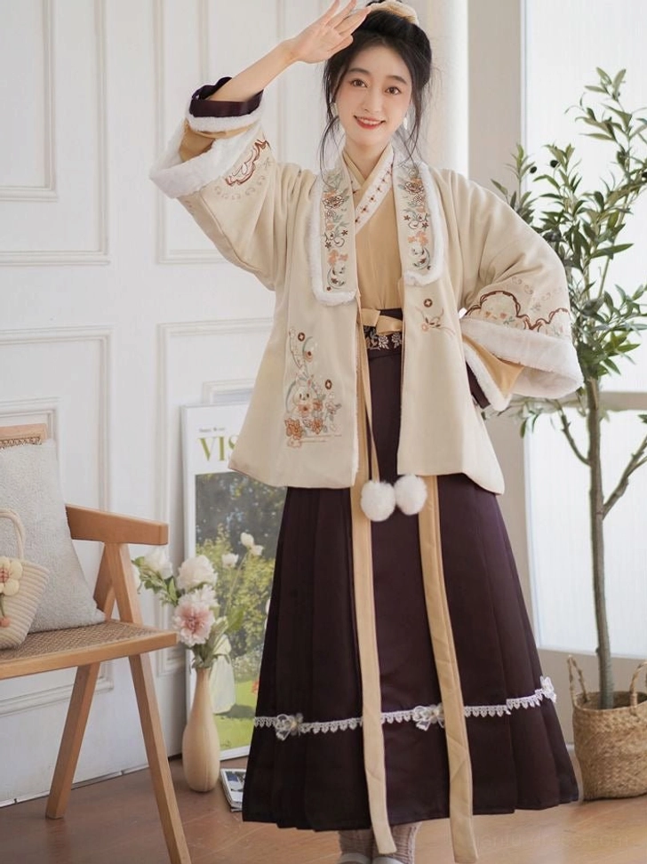 Three-quarter view of a contemporary Chinese Hanfu outfit with floral embroidered sleeves, long waist sashes, fluffy pom-pom pendants, and burgundy mamian skirt