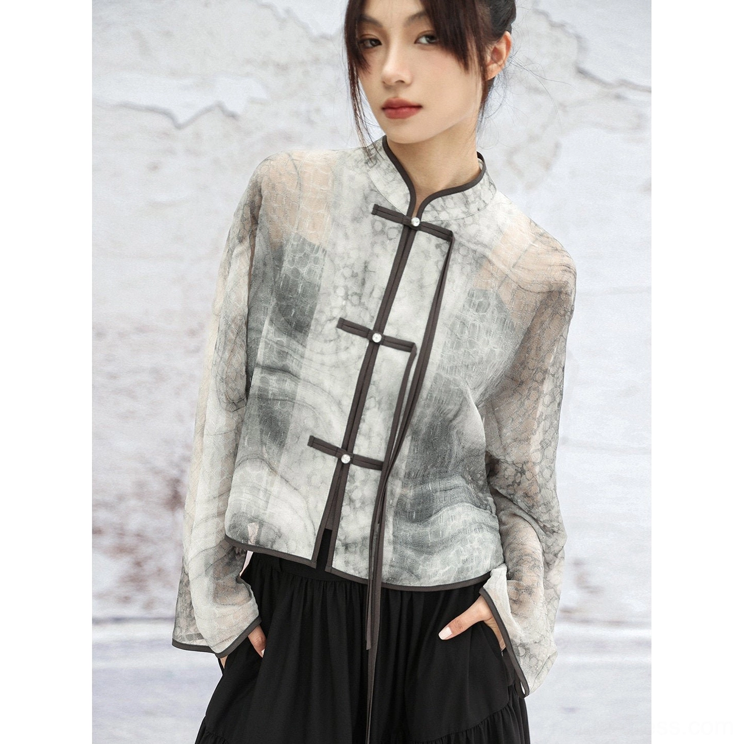 Half-side close-up of contemporary Chinese-inspired Hanfu jacket with cropped length, dark trims, frog buttons, and watercolor ink print