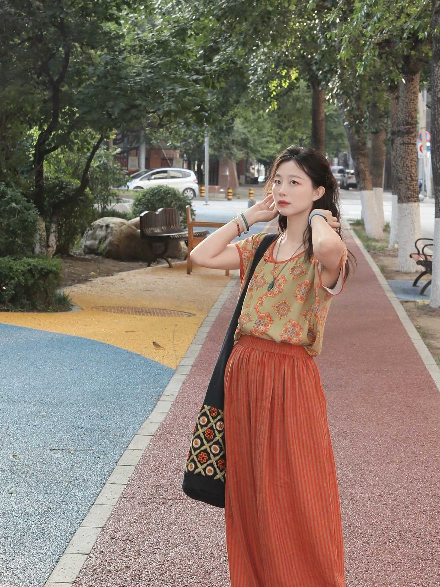 Side view of a contemporary Hanfu two-piece outfit featuring an olive-green floral printed top, rust-red neckline trim, and flowing striped wide-leg linen pants