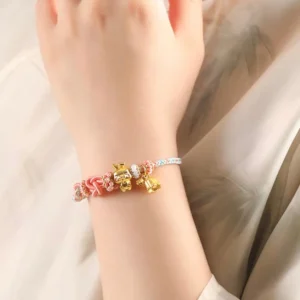 Handwoven cotton candy Chinese bracelet worn on wrist featuring pink Chinese knot details and playful golden charm
