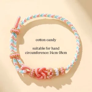 Cotton candy handwoven Chinese knot bracelet in pink light blue and white braided cord with gold thread accents on beige background