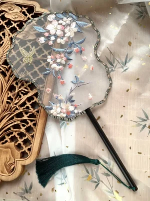 Crabapple blossom butterfly embroidered Chinese palace fan with translucent floral surface, scalloped lace-style border, dark wooden handle and green tassel
