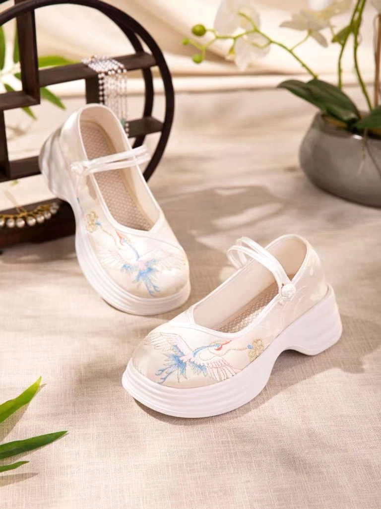 Oblique view of cream-white traditional Chinese Hanfu platform shoes with blue and gold red-crowned crane embroidery, Mary Jane strap, thick rubber sole, and breathable woven insole