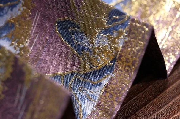 Close-up fabric detail of purple blue and gold Crane Returns mamianqun horse face skirt showing pleats and ornamental motifs