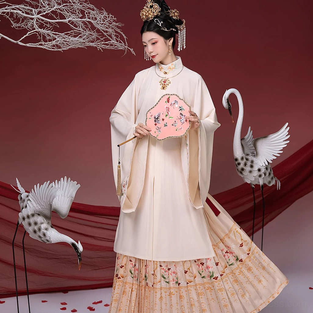 Front view of a cream-colored Ming-style bridal Hanfu outfit with stand collar robe, floral embroidered pleated skirt, gold trim, traditional hair ornaments, and floral round fan