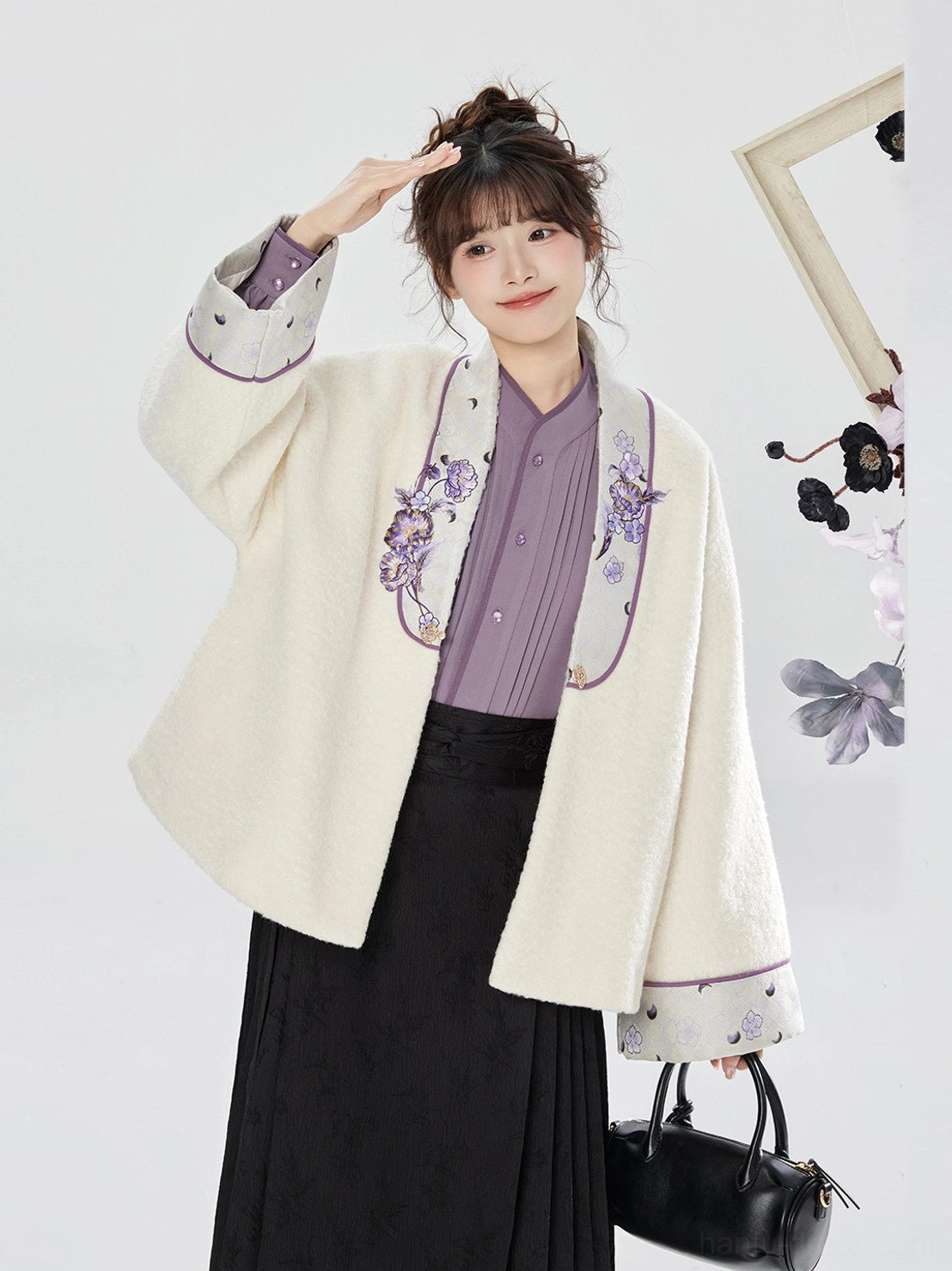 Close half-body view of a cream modern Ming hanfu jacket with purple floral embroidery, wide sleeves, and embroidered cuffs