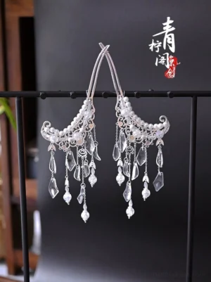 Pair of silver-tone crescent moon tassel Hanfu hair pins with pearl-like beads and clear crystal-style pendants displayed on a dark stand