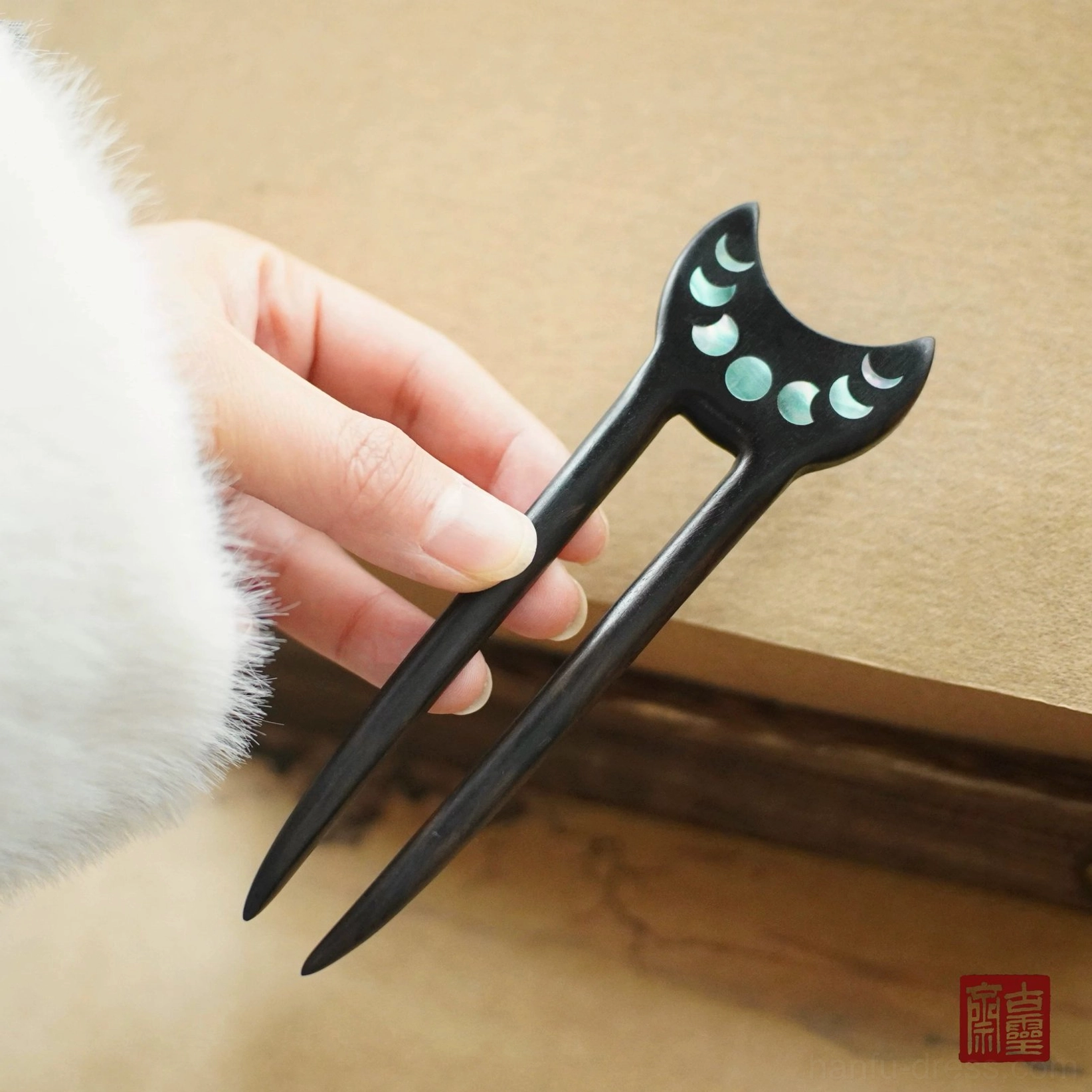 Crescent moon phase Hanfu hair stick with cyan inlay details and two pointed wooden prongs shown with traditional Chinese clothing