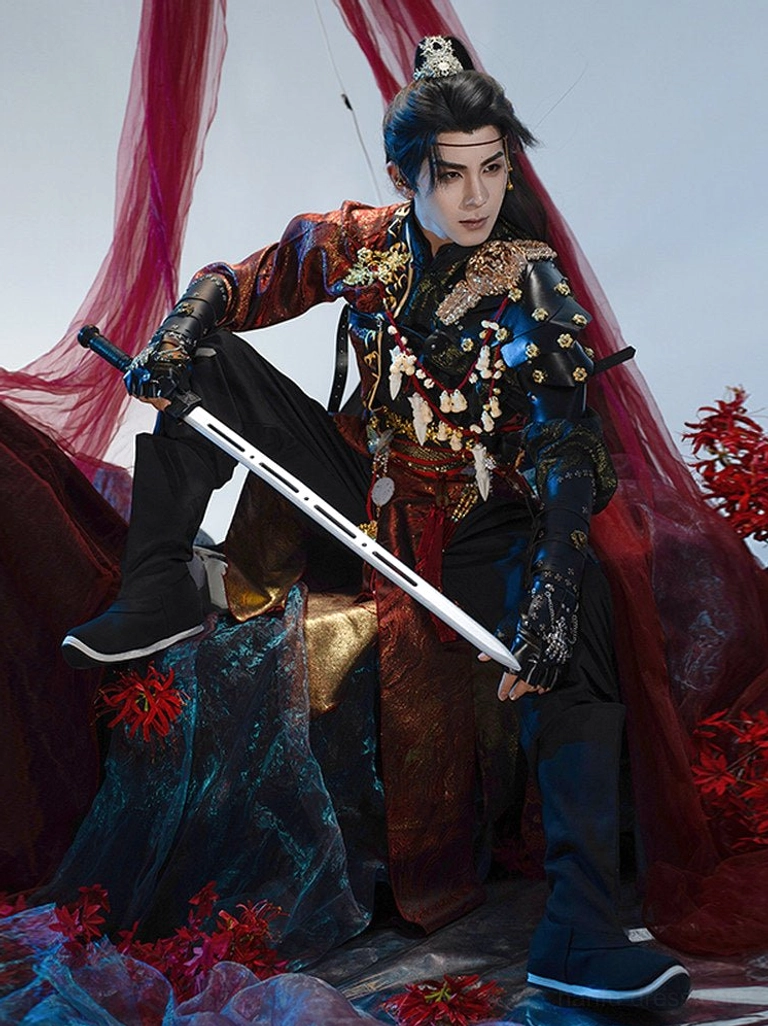 Male model wearing a crimson red and black Chinese wuxia warrior hanfu set with gold trim, wrist guards, waist ornaments, and a long white sword in a dramatic fantasy studio scene