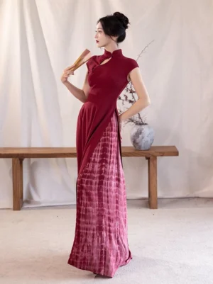 Crimson slit Ao Dai qipao dress shown in side profile with fitted bodice, asymmetrical hem, and vertical burgundy tie-dye maxi skirt