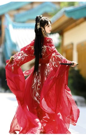 Back three quarter view of a crimson Wei Jin Dynasty princess Hanfu with golden floral embroidery, flowing sheer red fabric, beaded waist tassels, and elegant ancient Chinese hairstyle in a historic town setting