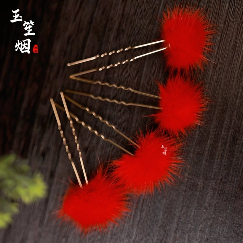 Curved arrangement of four red furball Chinese hair pins with twisted golden hair sticks and fluffy red ornaments