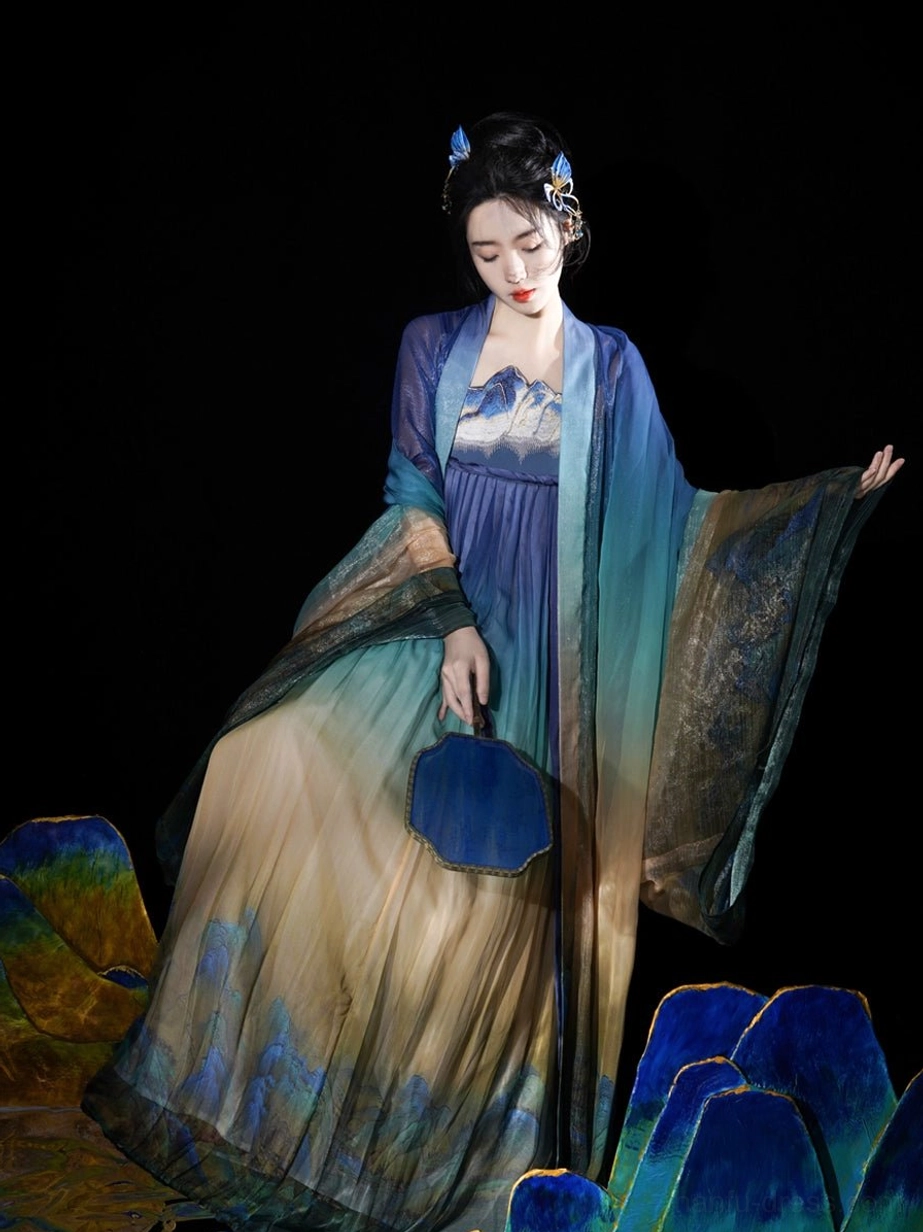 Daisy Blue Chinese Hanfu dress shown from the front with sheer wide sleeves gradient landscape pattern and blue round silk fan