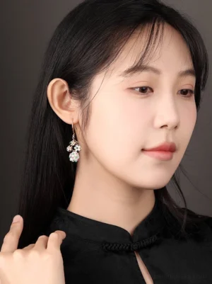 Model wearing daisy fairy floral dangle earrings with a black high collar cheongsam inspired traditional Chinese outfit