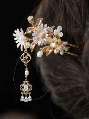 Daisy flower Chinese hair stick with gold-tone double prongs, imitation pearls, metal leaves, and crystal tassel displayed in a dark hair bun