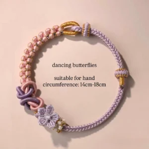 Dancing Butterflies handwoven Chinese knot bracelet in pastel purple pink and gold with braided cord flower ornament and traditional Chinese knots on a light pink background