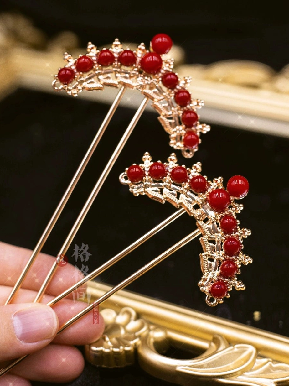 Red bead and gold-toned Chinese bridal hair sticks held in hand, showing detailed carved metal frames and crown-shaped ornaments