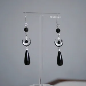 Pair of dark crescent Chinese Hanfu hook earrings with black beads ivory crescent charms and long black teardrop pendants on clear stand