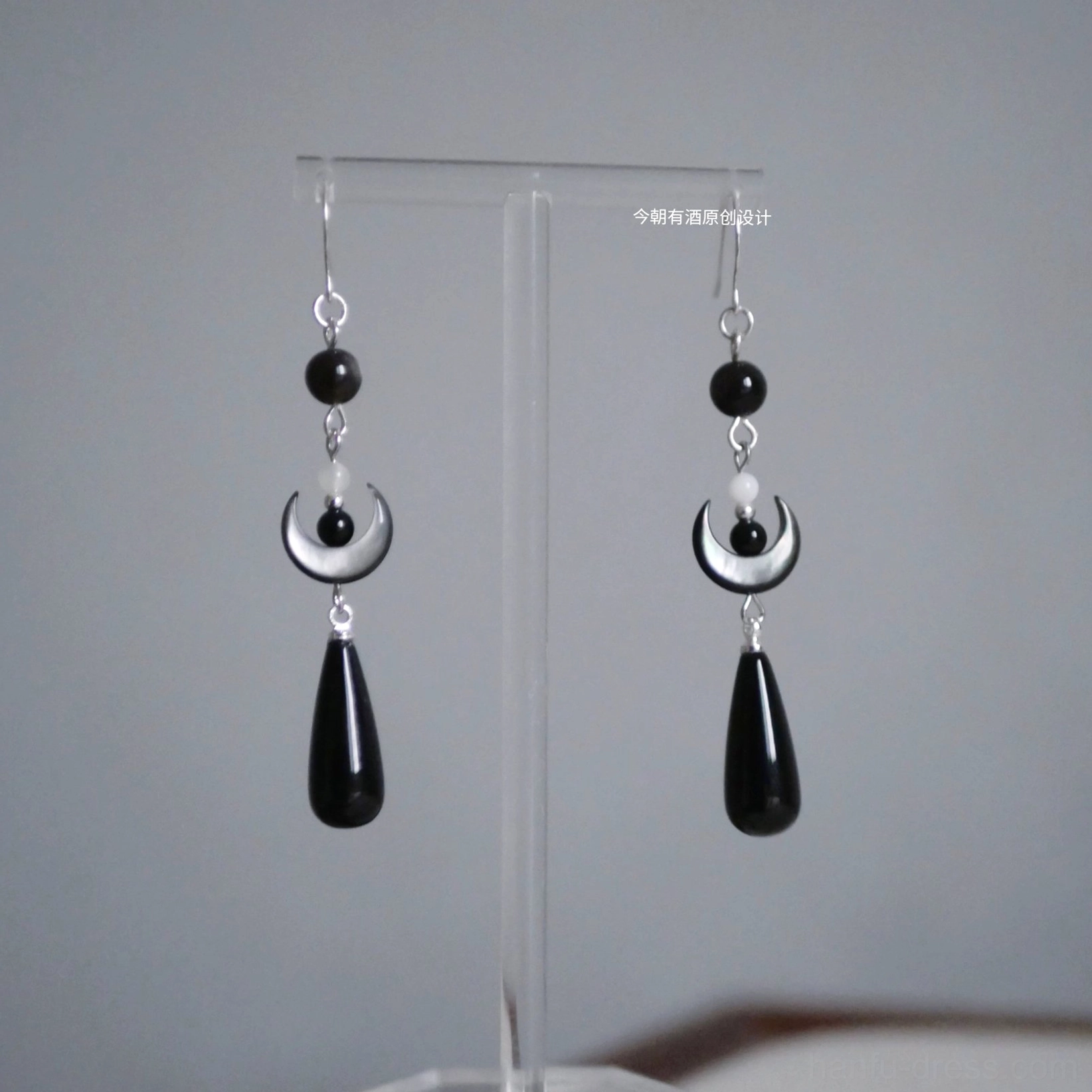 Pair of dark crescent Chinese Hanfu hook earrings with black beads ivory crescent charms and long black teardrop pendants on clear stand