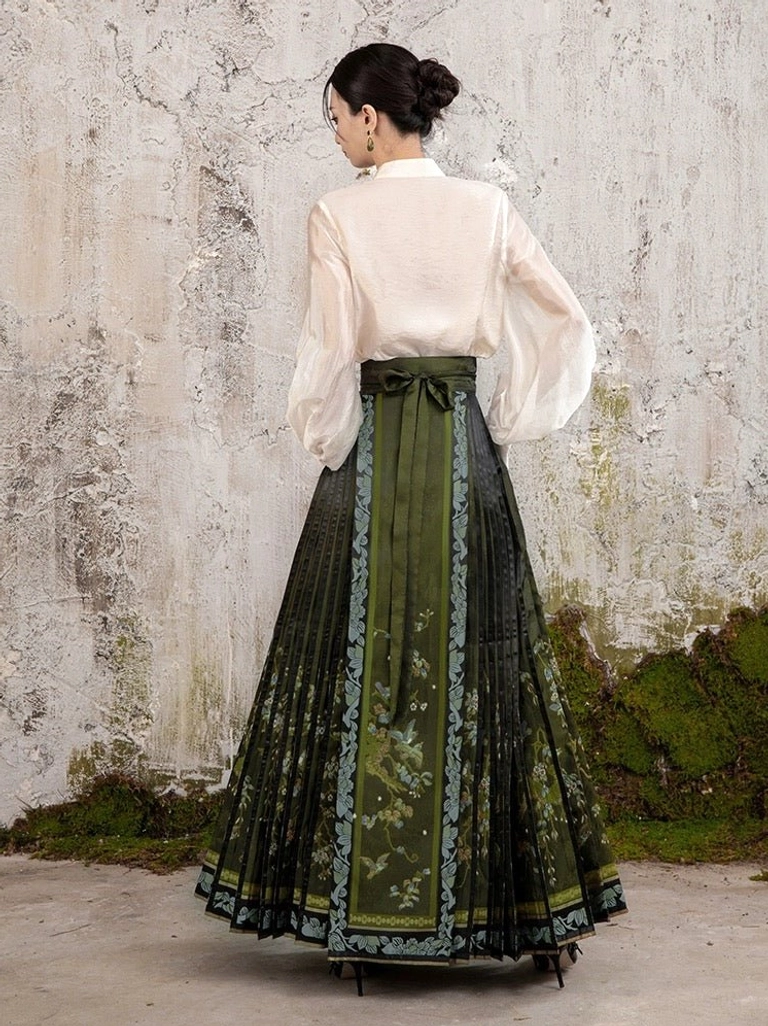 Rear view of a dark green modern Ming style mamian skirt showing the full pleated maxi design, back waist bow sash, floral details, and decorative trims