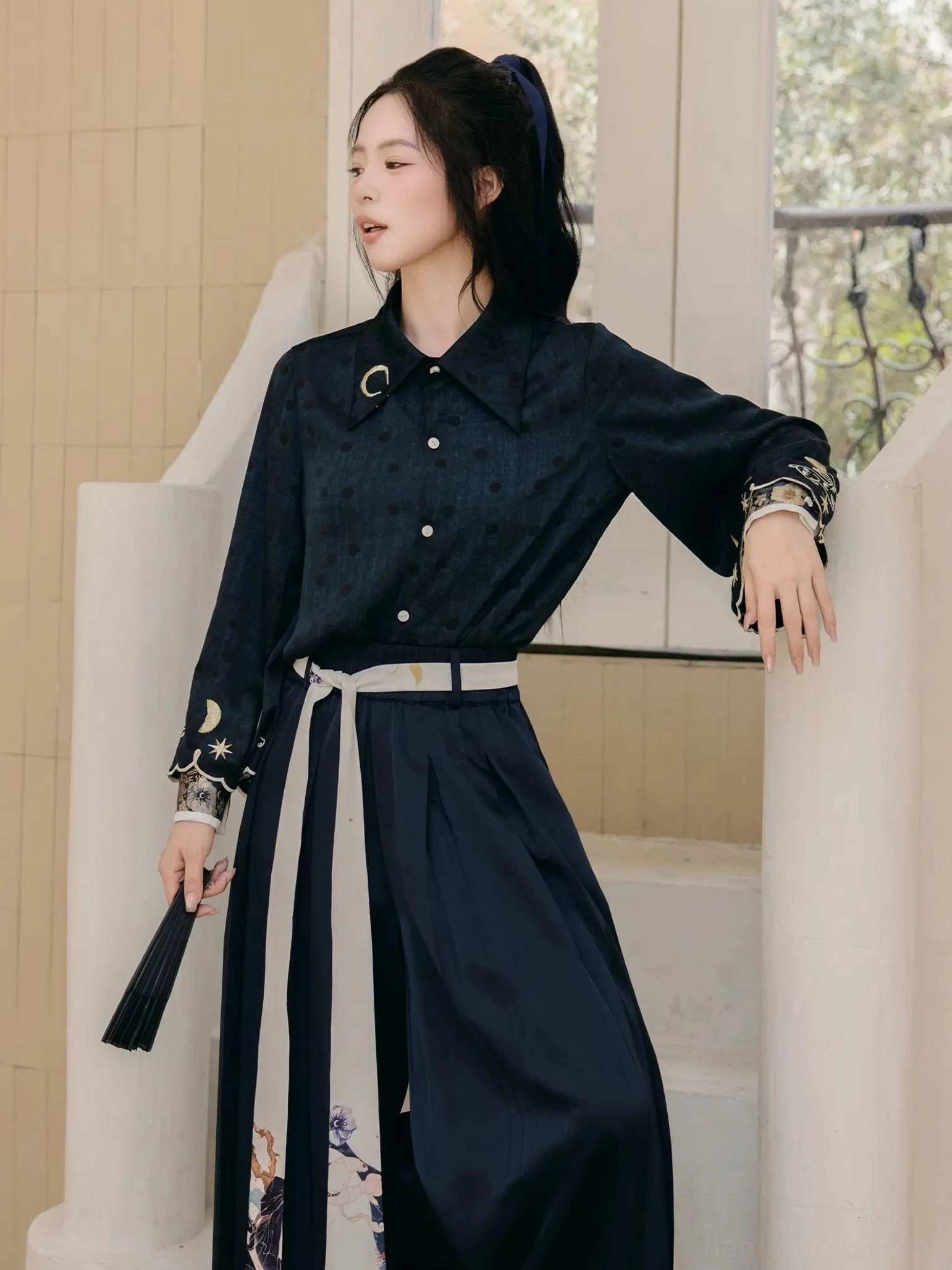 Flat lay display of a dark navy long-sleeve modern Hanfu blouse with subtle dotted fabric, star and moon embroidered cuffs, and metal collar ring