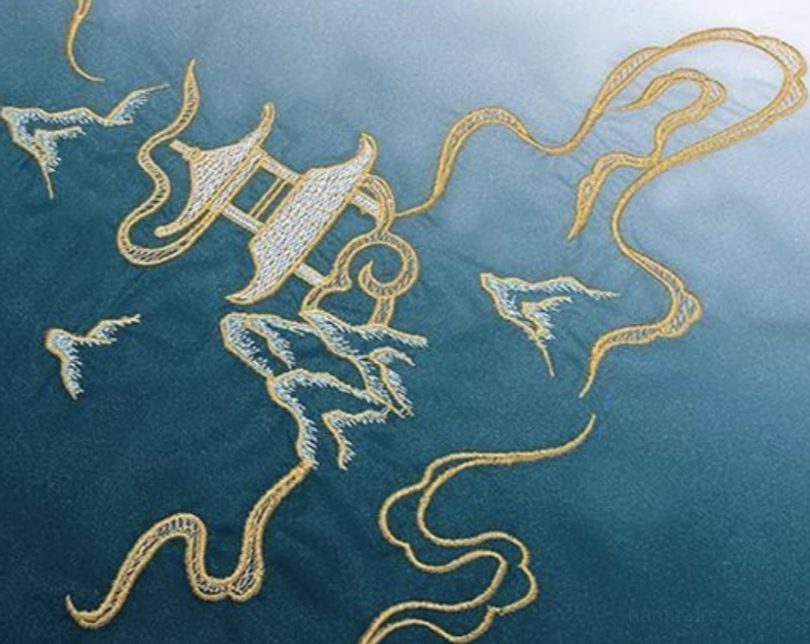 Close-up of dark teal hanfu fabric with gold thread embroidery depicting a mountain pavilion, flowing clouds, and a traditional landscape scene