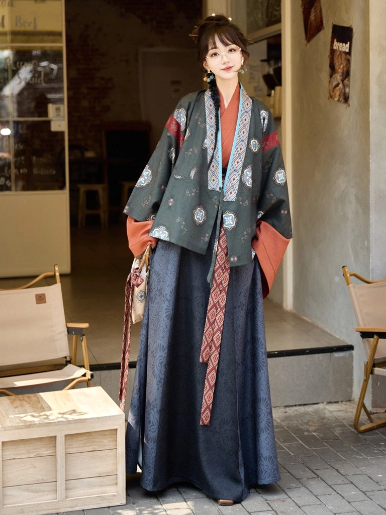 Dark teal Jin Dynasty inspired modern hanfu jacket with floral embroidery, geometric collar trim, coordinated sash, and patterned handbag