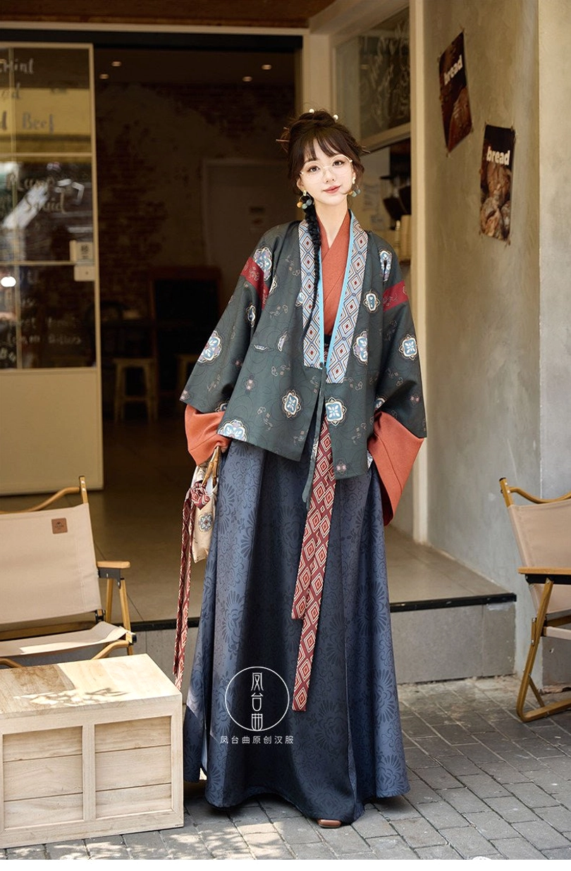 Dark teal modern hanfu full set with embroidered jacket, geometric collar and sleeve trims, matching waist sash, flowing skirt, and patterned handbag