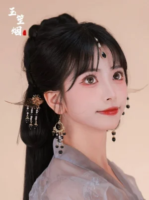 Side profile of a woman wearing grey Hanfu with a traditional updo, showing the gold wing hairpin, black beaded earring, and forehead pendant headdress