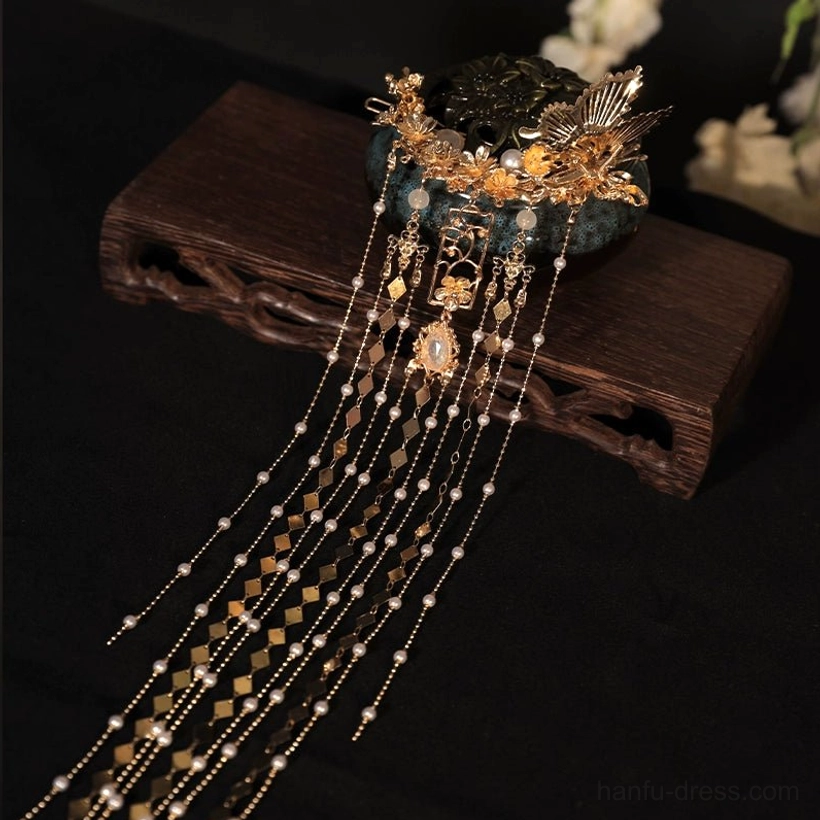 Overhead close-up of gold-toned traditional Chinese hairpin with layered bead tassels and geometric pendants