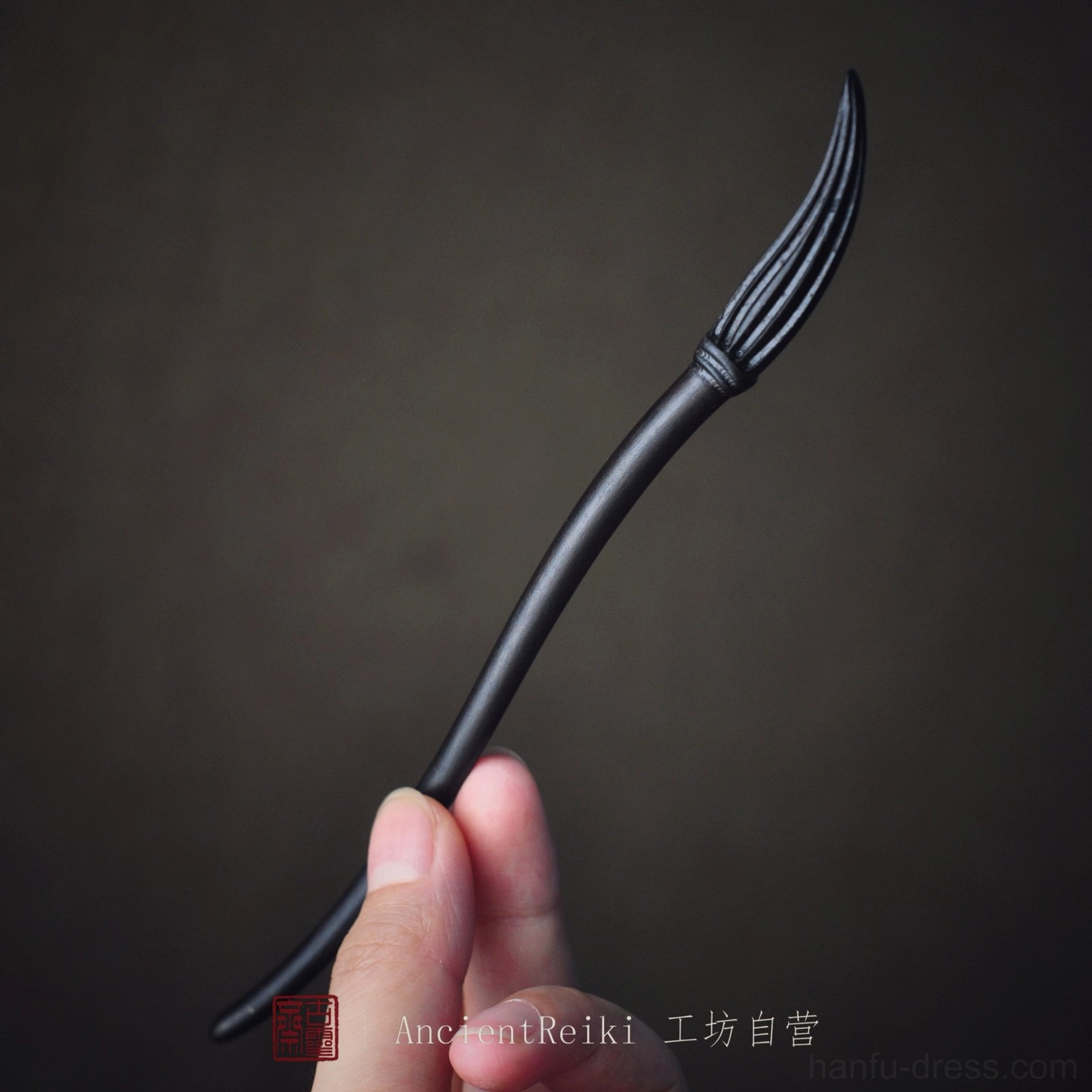 Deep purple black ink brush hairpin held in hand showing detailed carved brush bristles and curved Chinese hair stick shape