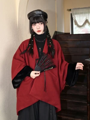 Full front view of deep red Chinese New Year cape with asymmetric hem, black faux fur cuffs, wrap front, and folding fan styling