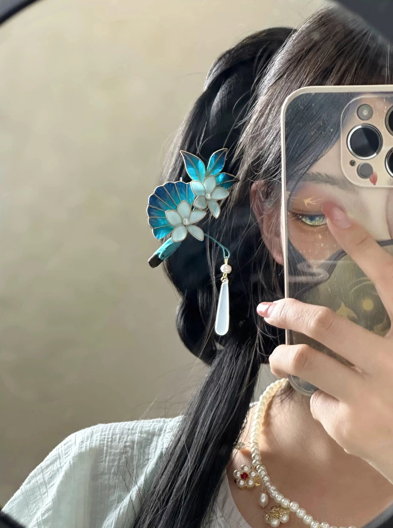 Model wearing deep sea blue floral Chinese hair stick on a side braid with linen Hanfu outfit and layered pearl necklaces