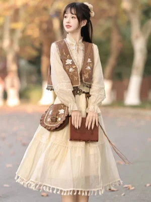 Desert Whisper modern Hanfu dress set worn outdoors, featuring a beige tassel hem midi dress, brown floral embroidered vest, and matching crossbody bag