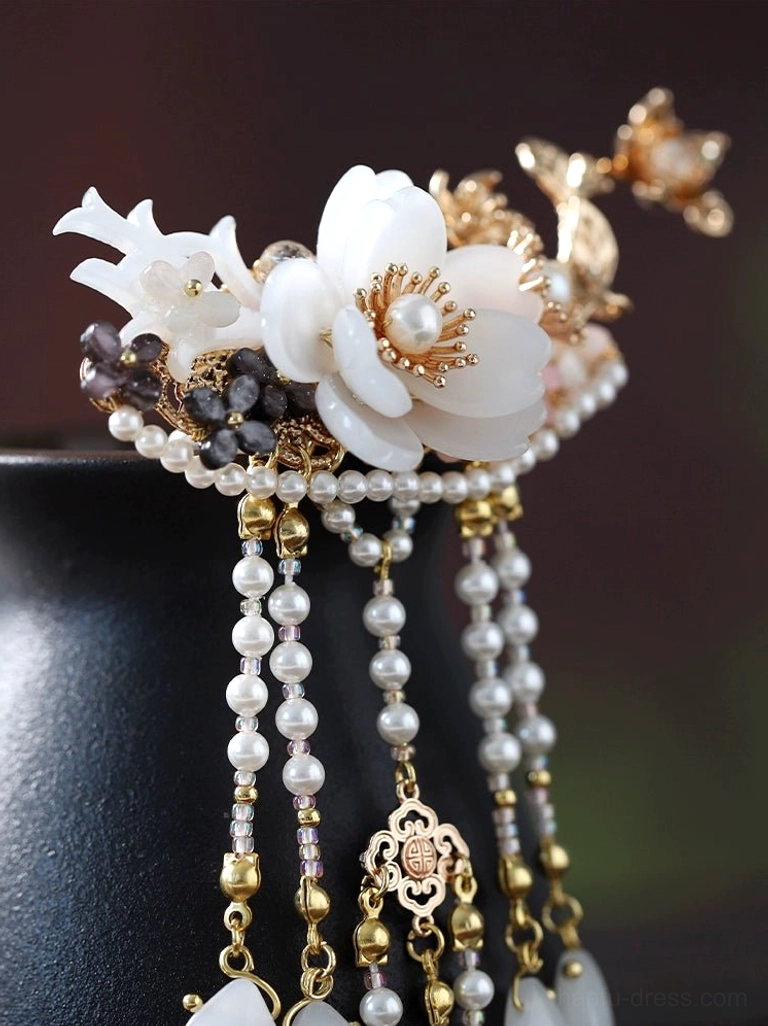 Detailed traditional Chinese hairpin close-up featuring large white flowers dark gem accents vintage metal charms and dangling tassels